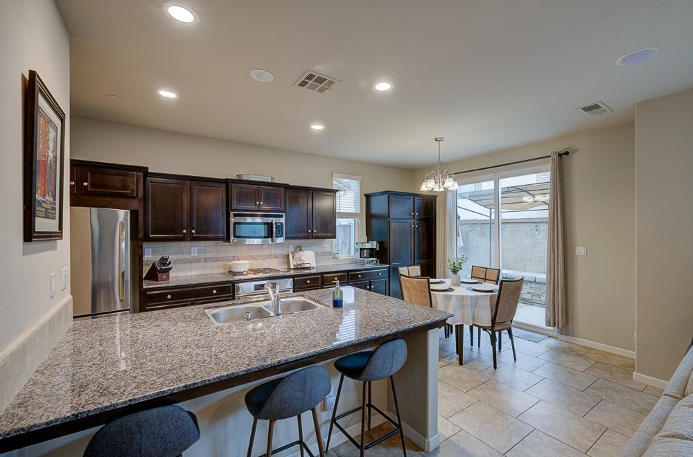 3518 Significant Way Clovis, CA 93619 - Photo 10 of 34 a kitchen with stainless steel appliances granite countertop a stove a refrigerator a sink a dining table and chairs