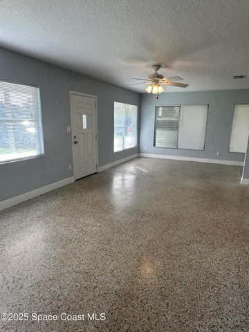 en empty room with windows and ceiling fan