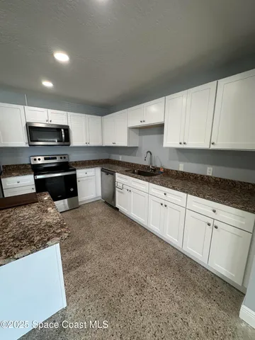 a kitchen with stainless steel appliances granite countertop a sink a stove a microwave and cabinets