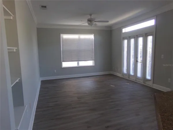 a view of an empty room with wooden floor and a window