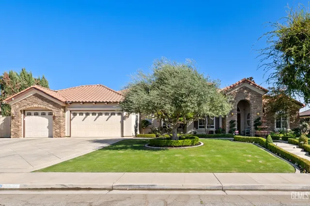 a view of a house with a big yard and large tree and plants