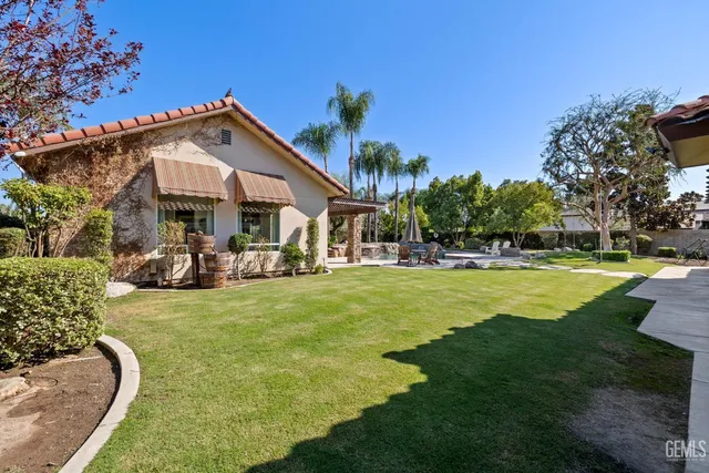 a view of a swimming pool with a table and chairs under palm trees