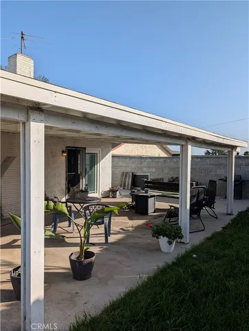 a view of a patio with table and chairs potted plants and floor to ceiling window