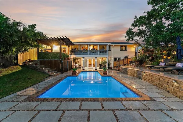 a view of a house with swimming pool lawn chairs and a yard