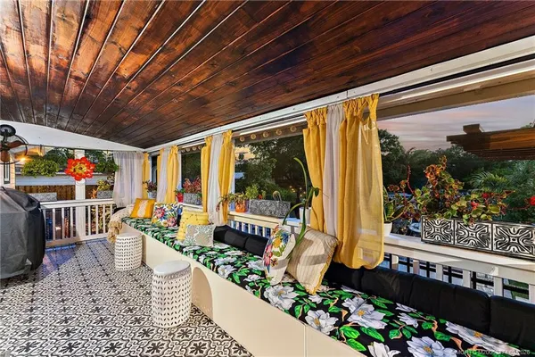 a view of swimming pool with lawn chairs plants and large trees