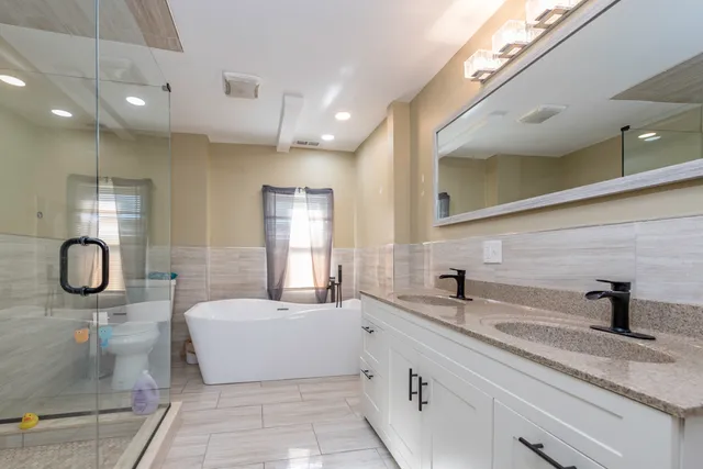 a bathroom with a granite countertop sink a toilet a mirror and shower