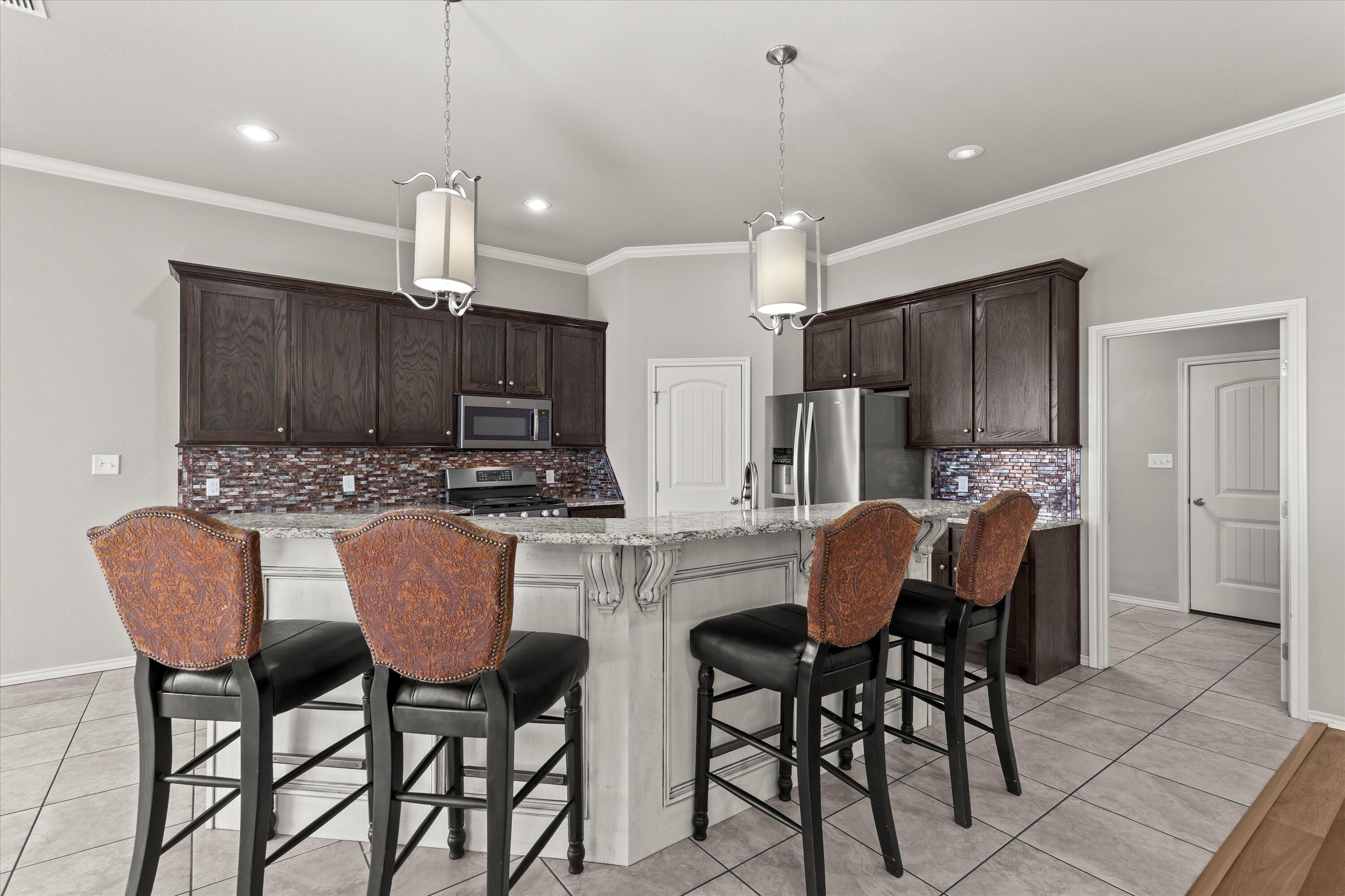 9616 Kline Avenue Lubbock, TX 79424 - Photo 11 of 33 a kitchen with stainless steel appliances kitchen island granite countertop a dining table chairs refrigerator sink and cabinets