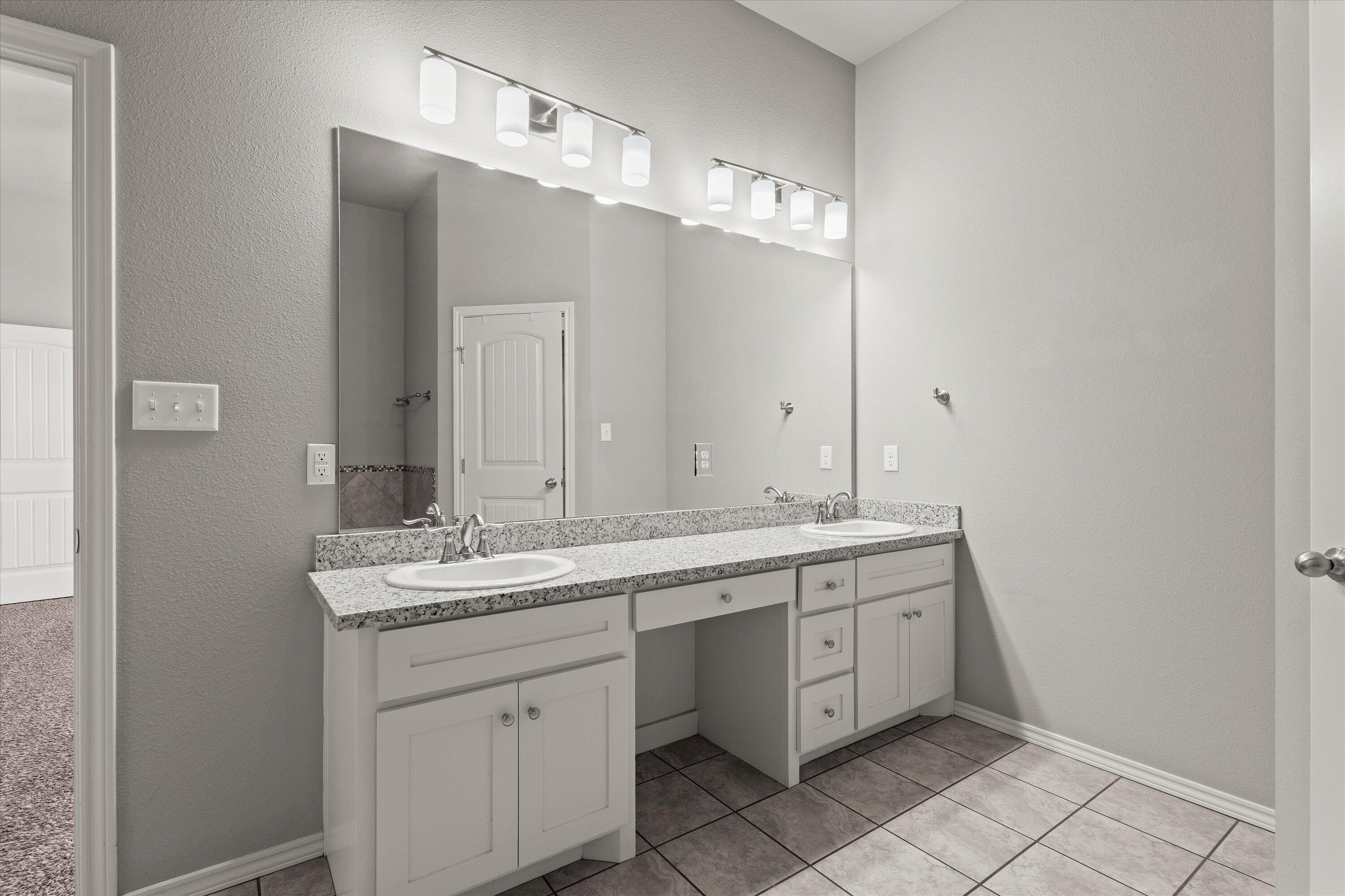 9616 Kline Avenue Lubbock, TX 79424 - Photo 17 of 33 a spacious bathroom with a double vanity sink and a mirror