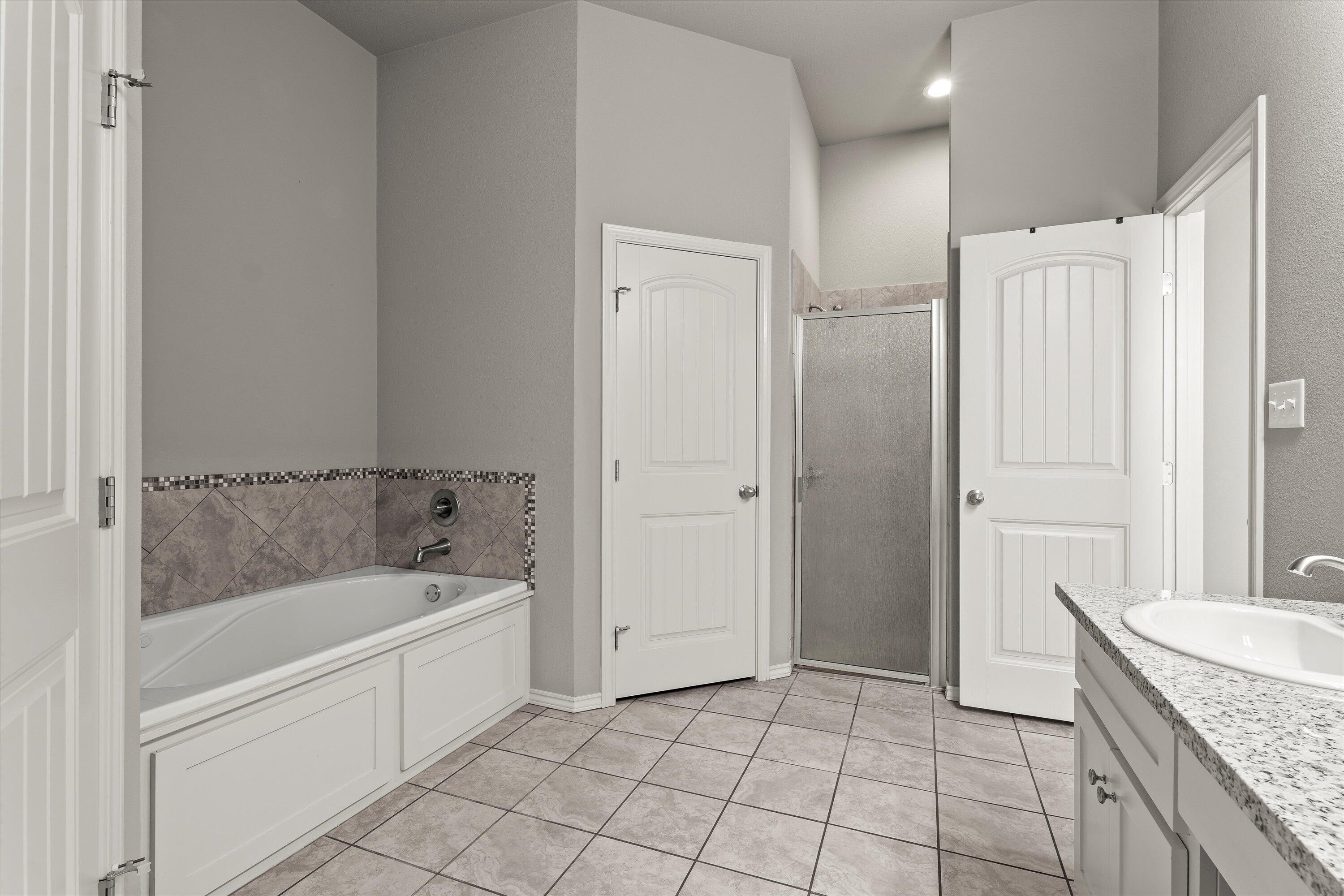 9616 Kline Avenue Lubbock, TX 79424 - Photo 18 of 33 a bathroom with a granite countertop sink a mirror and a bathtub