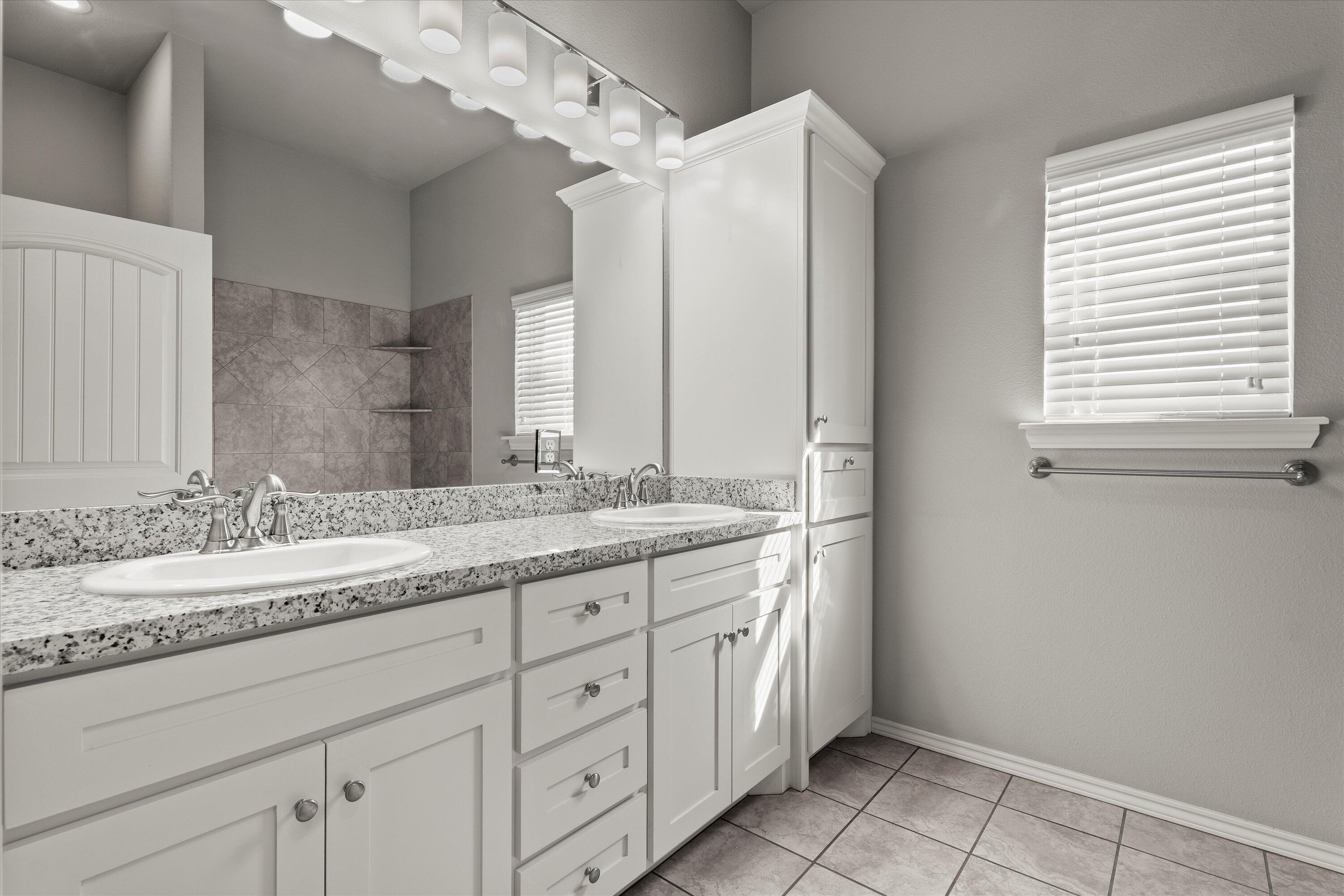 9616 Kline Avenue Lubbock, TX 79424 - Photo 24 of 33 a bathroom with a granite countertop sink a mirror and a