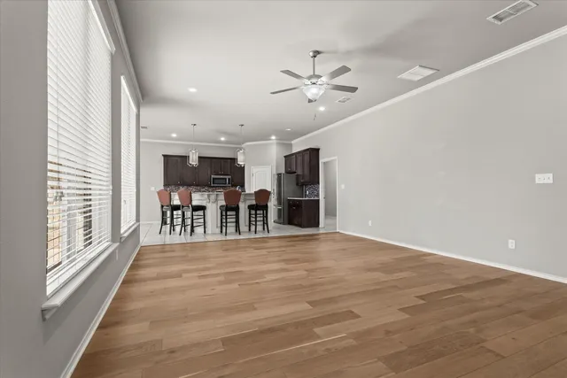 a kitchen with stainless steel appliances kitchen island granite countertop a dining table chairs refrigerator sink and cabinets