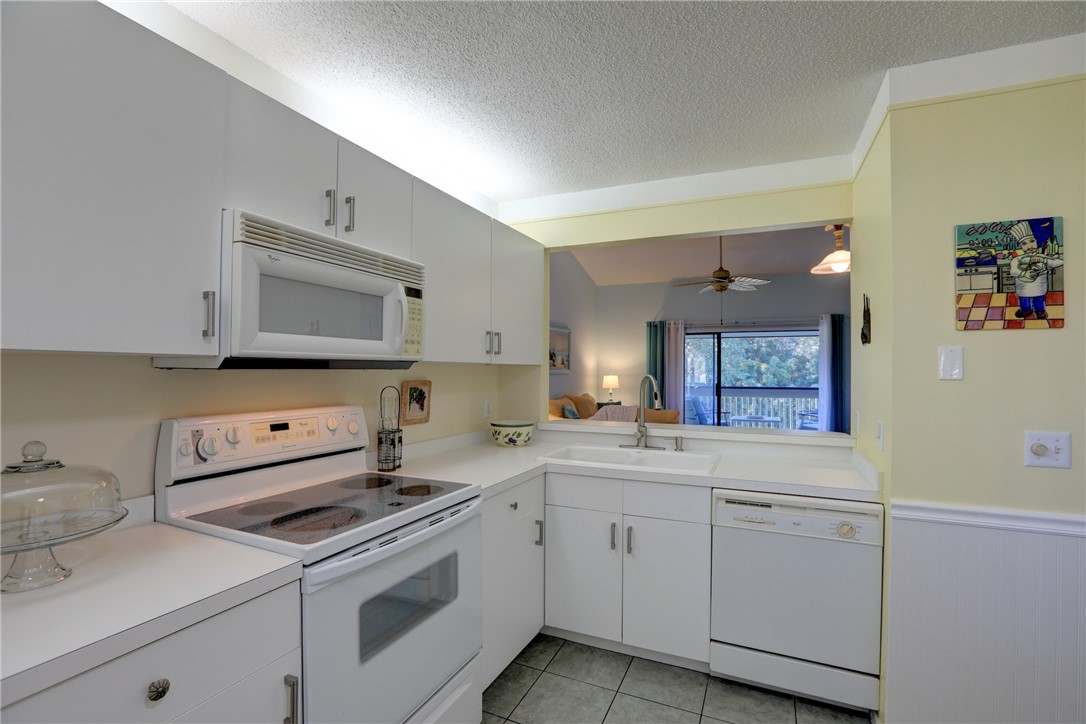 9635 Riverside Drive, Unit 4 Sebastian, FL 32958 - Photo 13 of 34 a kitchen with white cabinets and white appliances