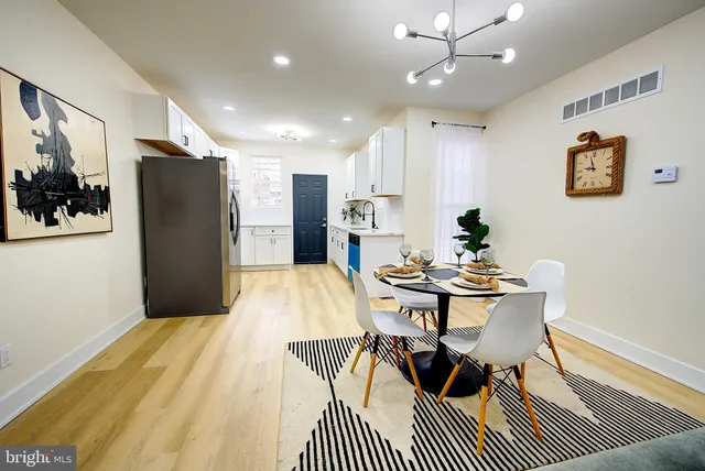 a kitchen with stainless steel appliances granite countertop a refrigerator a sink a stove a dining table and chairs