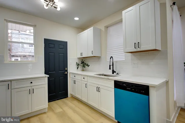a kitchen with white cabinets and sink