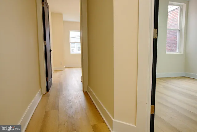 a view of a hallway with wooden floor and a bathroom
