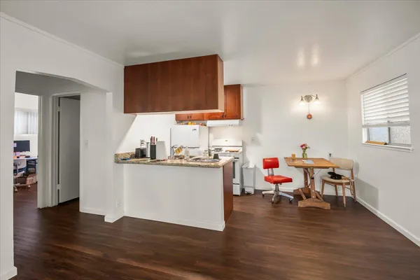 a living room with kitchen island granite countertop wooden floor and white walls