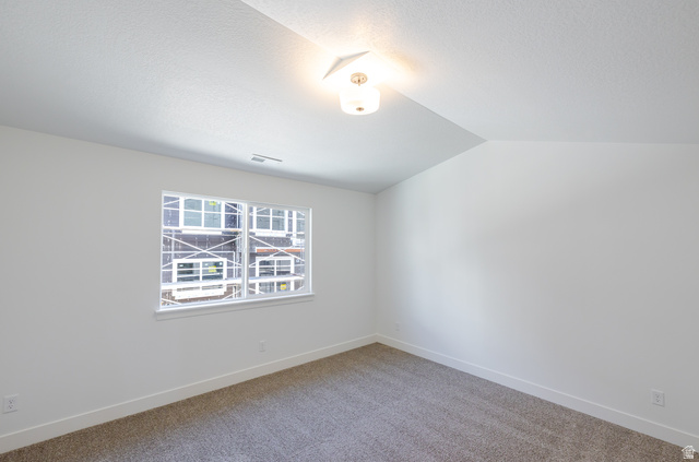 4809 Olive Avenue, Unit 417 Mapleton, UT 84664 - Photo 11 of 18 Carpeted spare room featuring lofted ceiling and baseboards