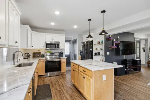 a kitchen with granite countertop kitchen island stainless steel appliances and wooden cabinets