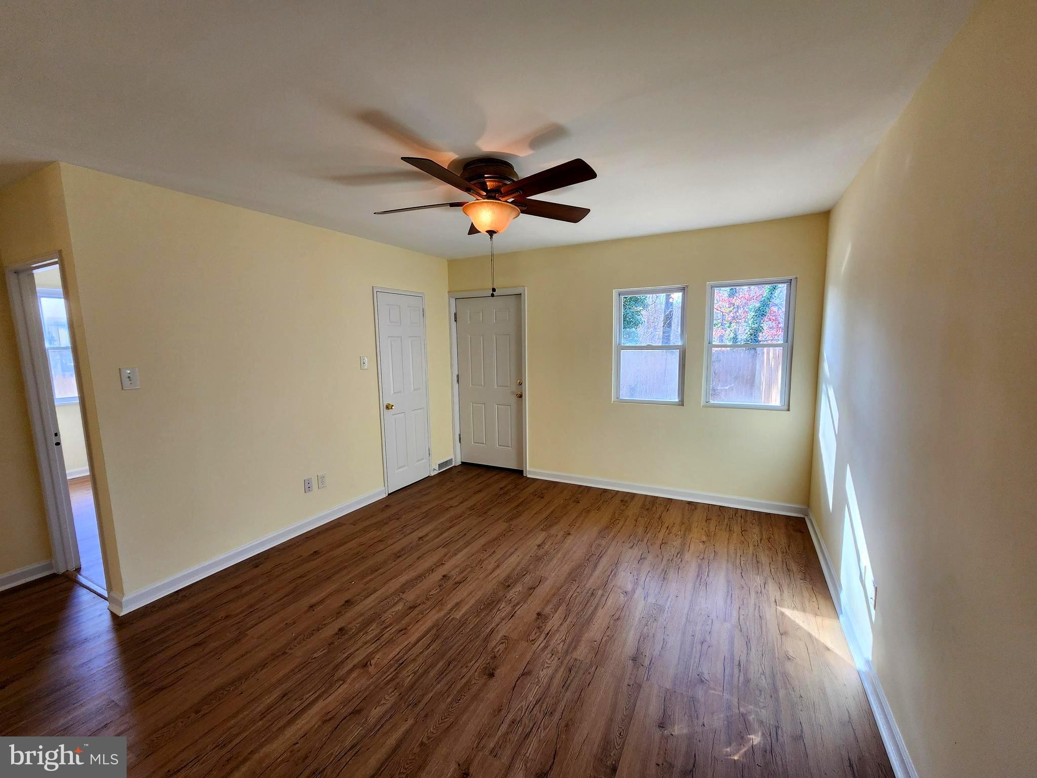 7533 Greenleaf Road Landover, MD 20785 - Photo 11 of 36 an empty room with wooden floor chandelier fan and windows