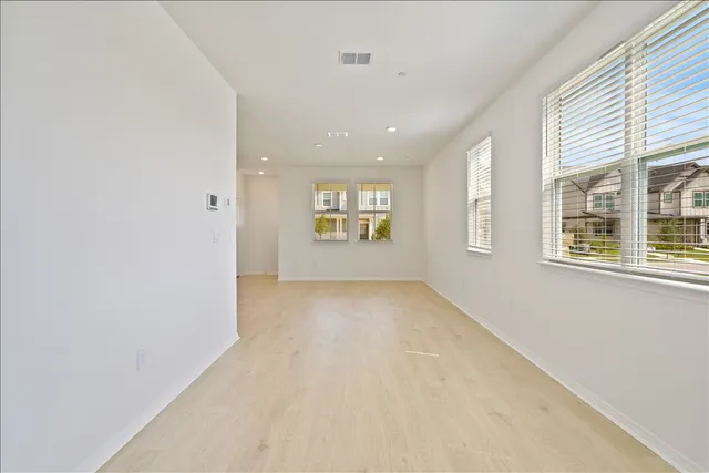 an empty room with white cabinet and windows