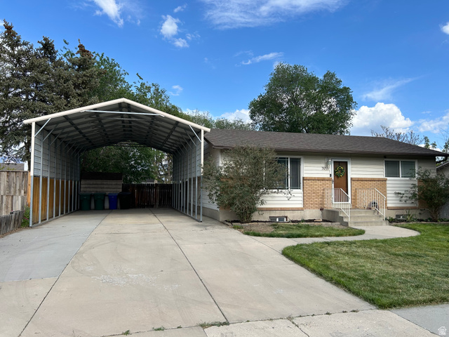 View of front of house featuring brick siding, a carport, and driveway