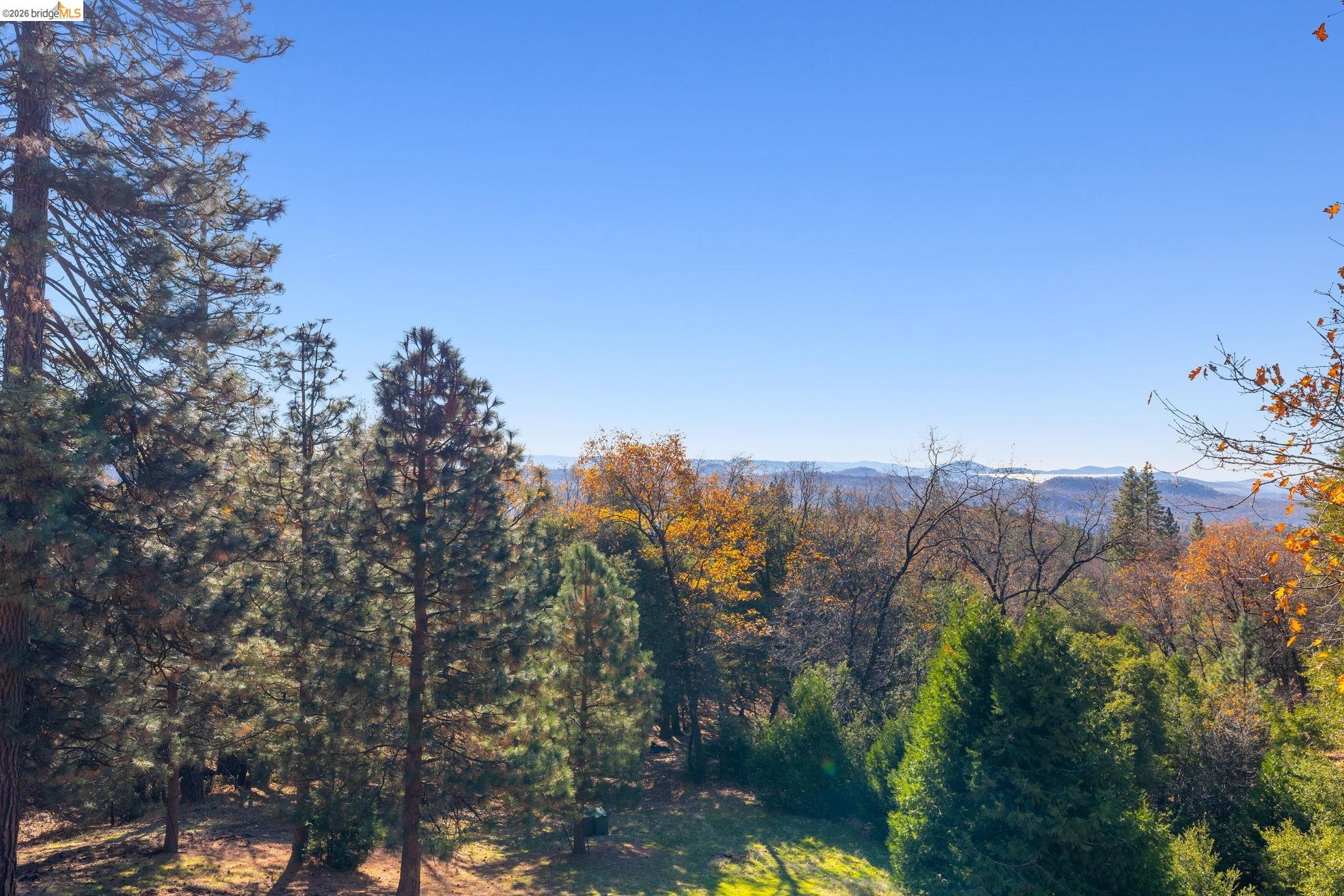16144 Big Hill Road Sonora, CA 95370 - Photo 38 of 51 Expansive natural landscape featuring a variety of mature trees and distant mountain ranges under a clear sky