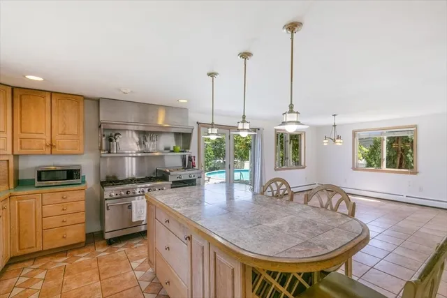 a kitchen with stainless steel appliances granite countertop a kitchen island a stove a refrigerator and a view of living room