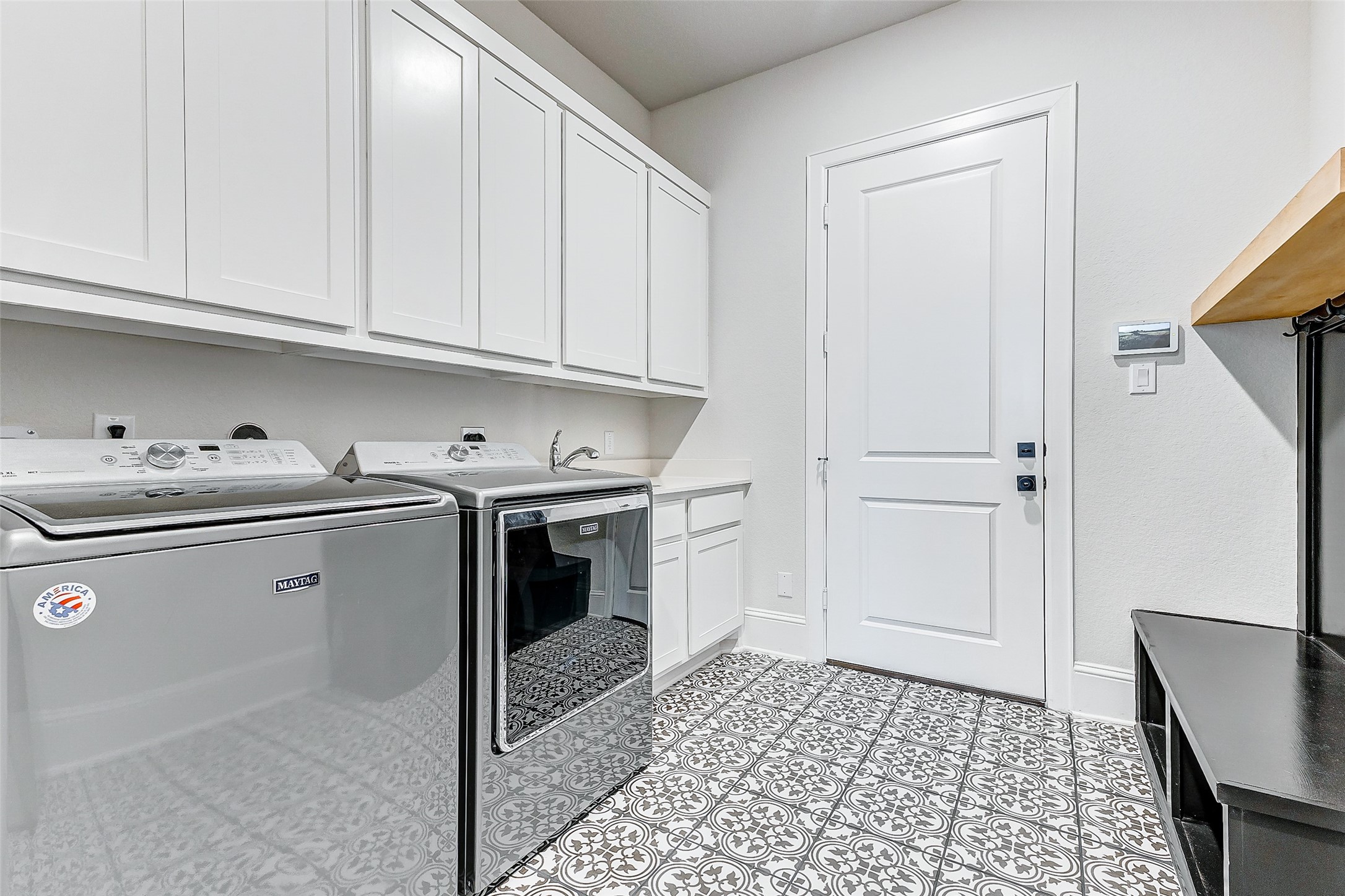 5318 Streamside Trail Fulshear, TX 77441 - Photo 20 of 43 The laundry room features custom tile flooring, a built-in mud bench, and a utility sink with cabinet storage below, offering convenience and organization. Overhead cabinets span across one wall, providing extensive storage capacity for all necessities.