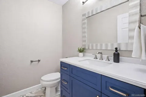 a bathroom with a granite countertop sink vanity mirror and toilet