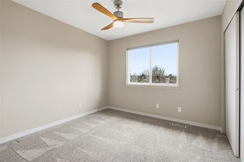 an empty room with window and ceiling fan