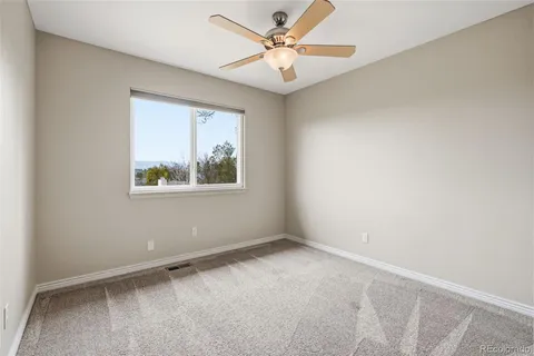 an empty room with a window and a ceiling fan