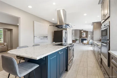 a kitchen with stainless steel appliances kitchen island granite countertop a table chairs in it and wooden floors