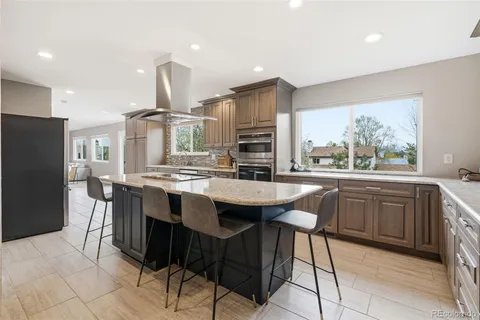 a kitchen with stainless steel appliances kitchen island granite countertop a sink a stove a refrigerator and a dining table with wooden floor
