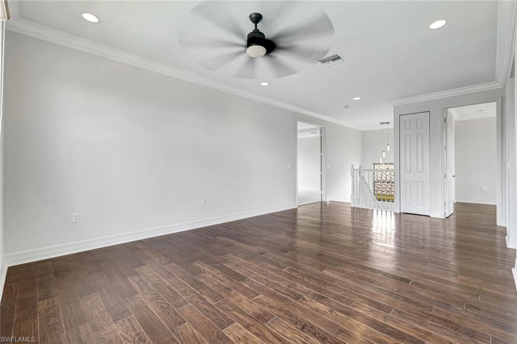3430 Tigris Lane Naples, FL 34119 - Photo 16 of 48 a view of an empty room with wooden floor and a ceiling fan