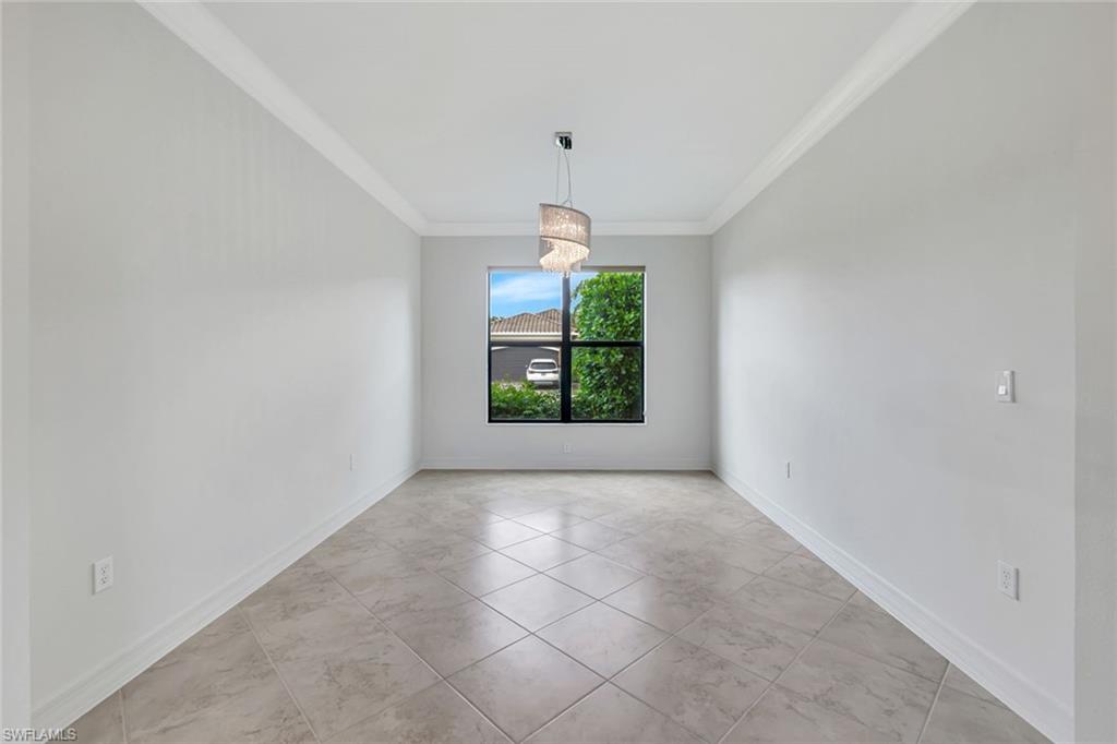 3430 Tigris Lane Naples, FL 34119 - Photo 23 of 48 an empty room with windows and chandelier
