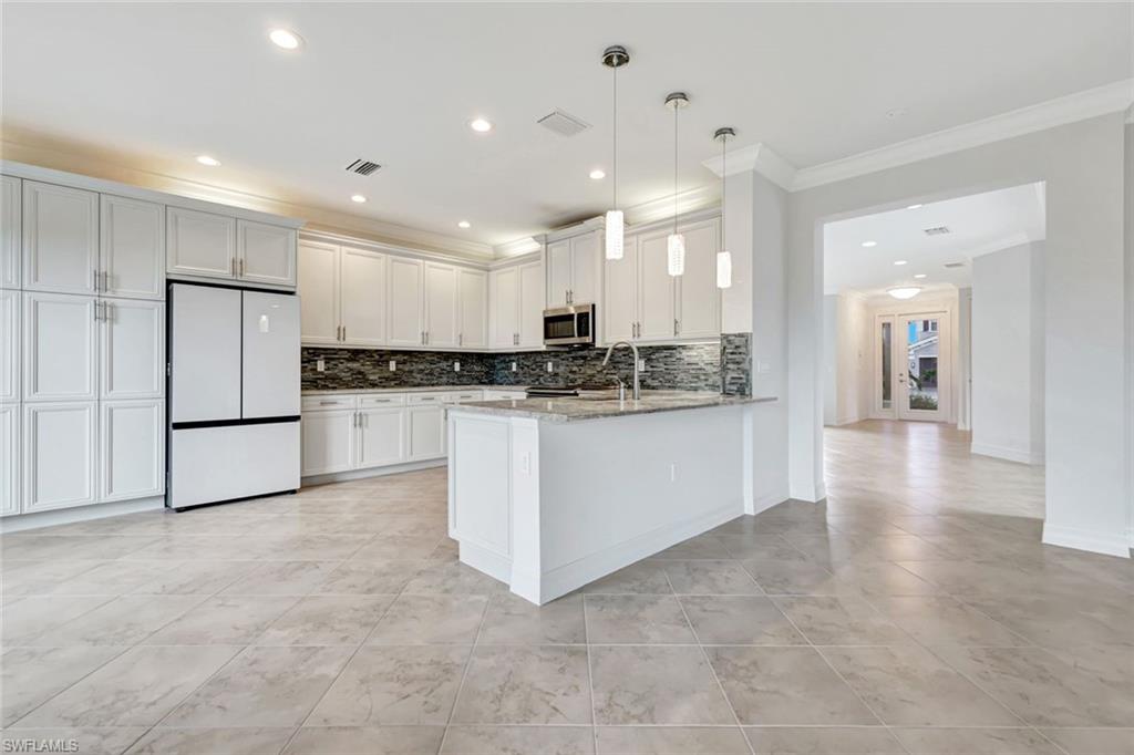 3430 Tigris Lane Naples, FL 34119 - Photo 5 of 48 a large kitchen with stainless steel appliances granite countertop a stove a sink a refrigerator and white cabinets