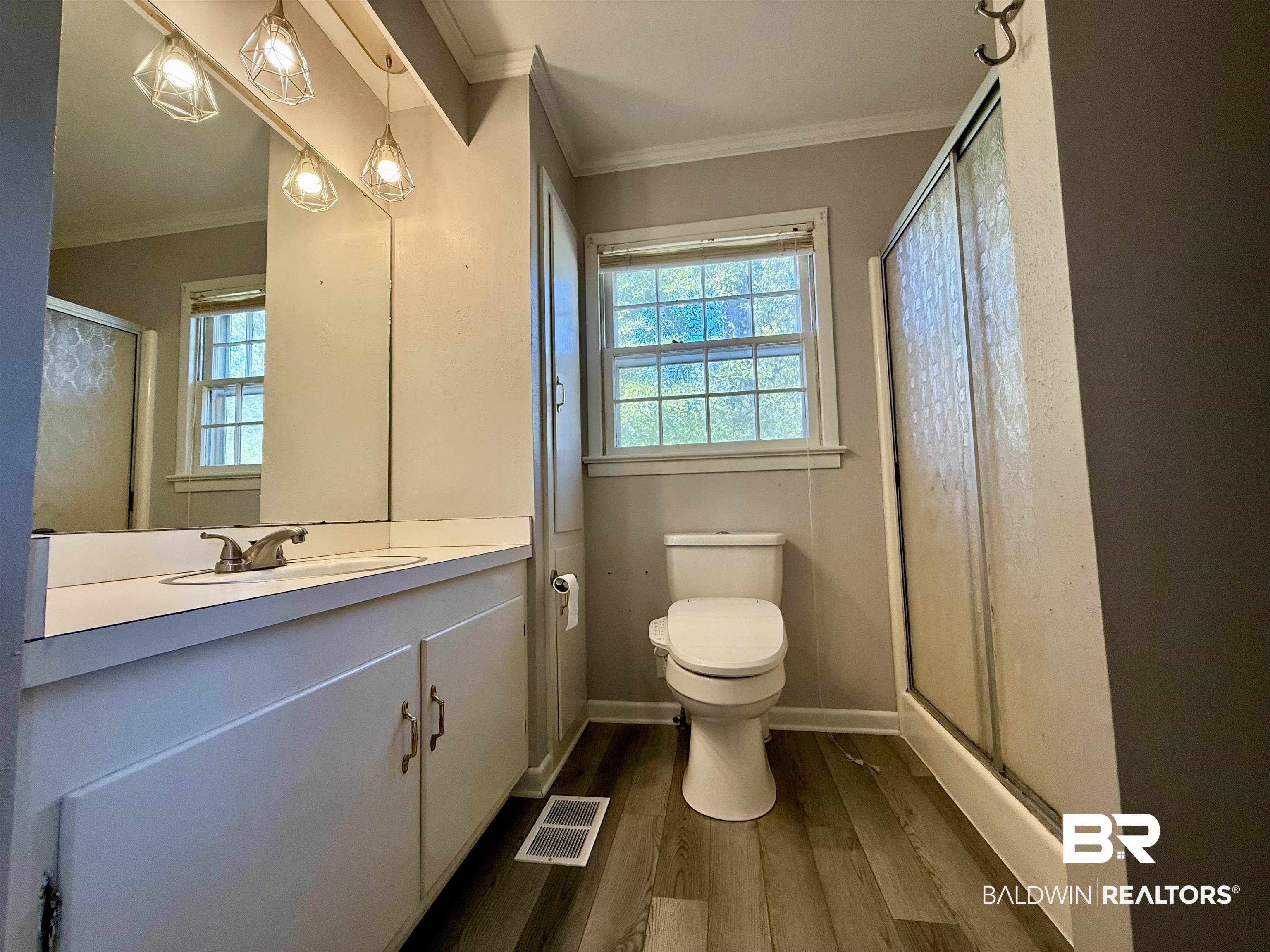 2785 Appleton Road Brewton, AL 36426 - Photo 16 of 28 Bathroom featuring crown molding, a shower stall, vanity, plenty of natural light, and dark wood-style flooring