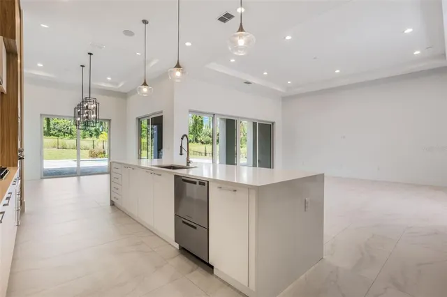 a large kitchen with kitchen island a large counter top a stove a sink and a large window