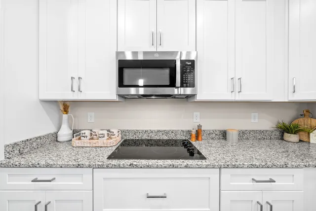 a kitchen with granite countertop white cabinets and a sink