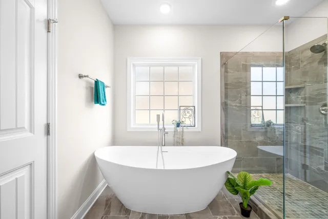 a white bath tub sitting in a bathroom next to a window