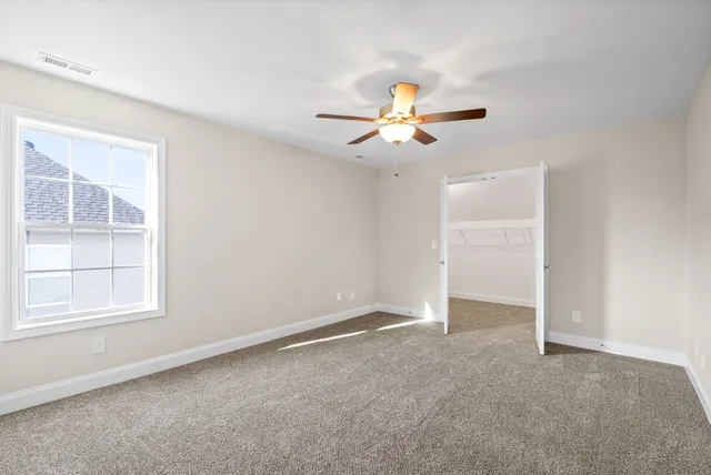 an empty room with windows and chandelier fan