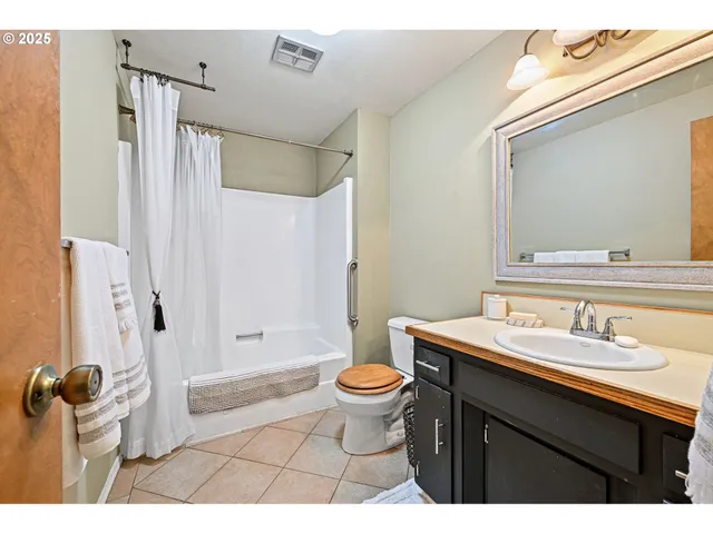a bathroom with a sink a toilet a mirror a vanity and shower