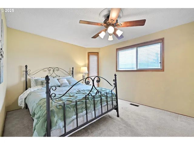 a bedroom with a bed next to a window with a chandelier