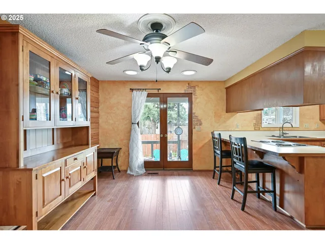 a open kitchen with stainless steel appliances granite countertop a stove top oven a dining table and chairs with wooden floor