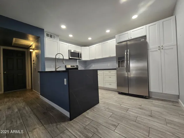 a kitchen with kitchen island a counter top space cabinets and stainless steel appliances