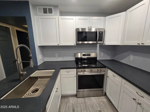 a kitchen with stainless steel appliances granite countertop a stove a sink and a microwave