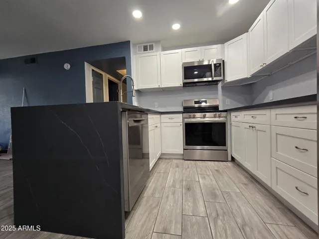 a kitchen with stainless steel appliances granite countertop a refrigerator and a stove top oven