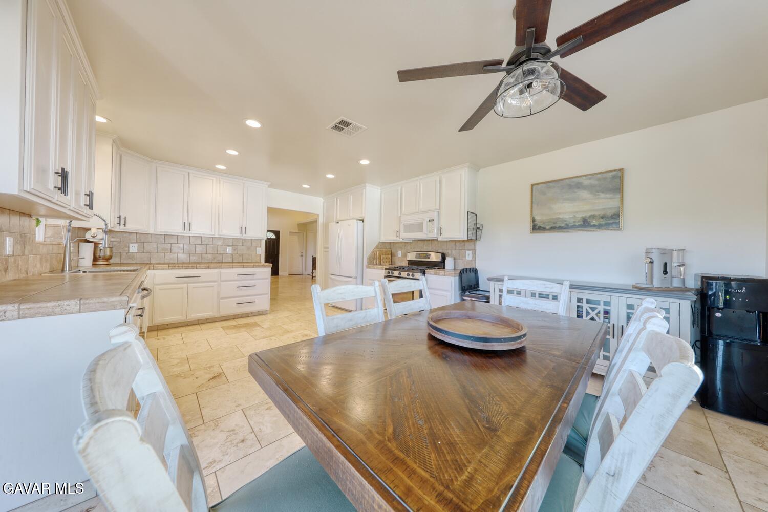 22311 Zurich Drive Tehachapi, CA 93561 - Photo 11 of 37 a kitchen with stainless steel appliances granite countertop a stove a refrigerator a sink a dining table and chairs with wooden floor