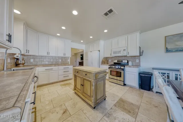 a kitchen with stainless steel appliances granite countertop a stove top oven a sink and a refrigerator