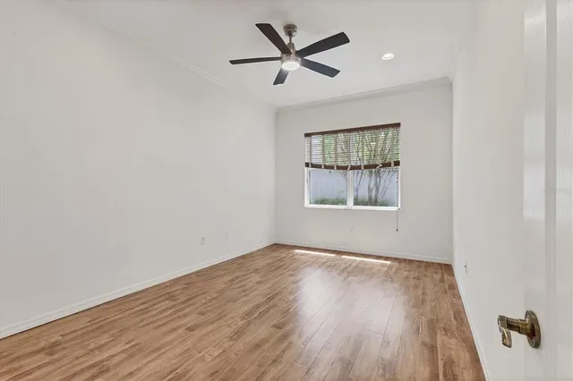 an empty room with wooden floor ceiling fan and windows